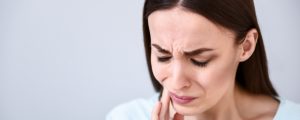 brunette woman holding mouth in pain from sinus pressure toothache