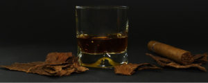 glass of whiskey with cigar, tobacco leaves and oral cancer threat